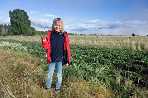 Strawberries: Girl - standing beside a strawberry field showing