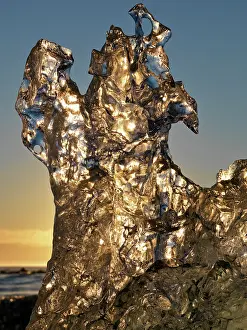 Environmentalism: Golden sunrise seen through iceberg formation