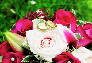 Rings: Golden wedding rings on a bridal bouquet with pink