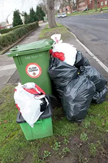 Overflowing: Green wheelie bin overflowing with domestic rubbish