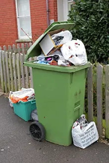 Overflowing: Green wheelie bin overflowing with domestic rubbish
