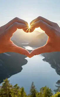 Forms: Hand forms a heart in front of alps and mountain