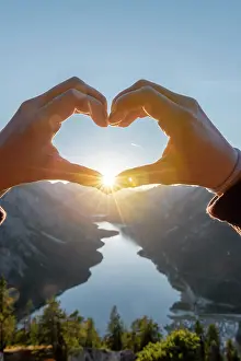 Forms: Hand forms a heart in front of alps and mountain