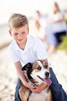 Attractive: Handsome young boy playing with his dog at the beach