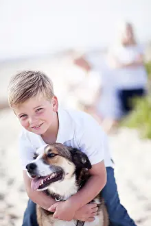 Attractive: Handsome young boy playing with his dog at the beach
