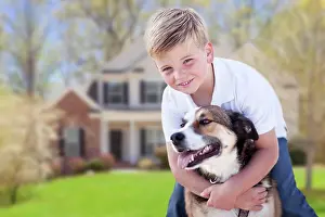 Neighborhood: Happy young boy and his dog in front yard of their house