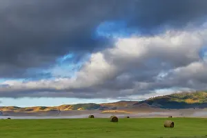 Bales: Hay bales in clearing fog with Salish Mountains