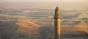 Sun Sets: Historic Ulu Cami mosque minaret in Mardin Turkey illuminated by sunset against vast Mesopotamian plains