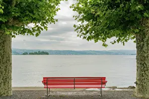 Plane: Horizontal shot of a red park bench on a lake shore