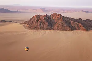 Remote: The hot-air balloon above an arid plain and isolated mountain ridges at the edge of the Namib Desert