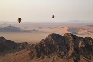 Remote: Two hot-air balloons above an arid plain and isolated mountain ridges at the edge of the Namib Desert