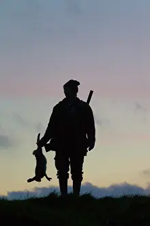 Hunters: Hunter hare Hunter with dead brown Hare silhouetted agai