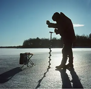 Drilling: Ice fishing with drill in winter