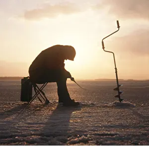 Fisherman: Ice fishing - using drill in winter