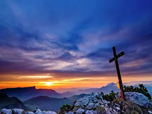 Berchtesgaden: Iceberg summit cross and cloudy atmosphere at sunrise