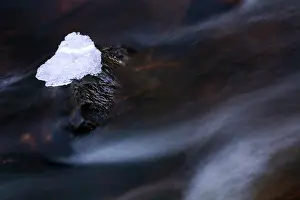 Streaming: Iceblock on rock in fast flowing water
