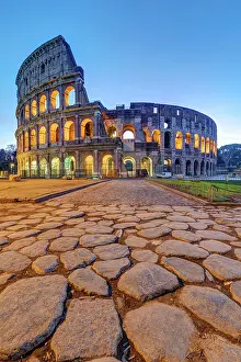 Daybreak: The illuminated Colosseum in Rome at dawn with l