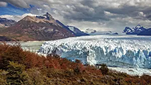 Glaciers: Imposing glacier front in a majestic mountain landscape with autumnal trees and dramatic skies