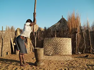 Pounding: Kavango woman pounding grain inside her homestead