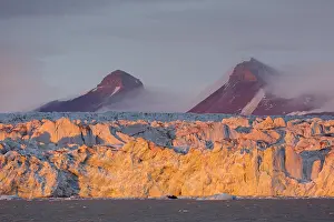 Calving: Kongsbreen glacier in evening light at sunset, calving into