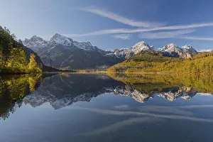 Journey: Lake Almsee in autumn with a forest and mountains reflected in the lake