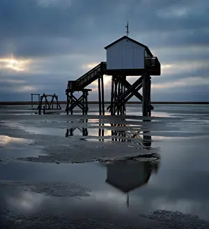 Gloomy: Lake house at low tide on the beach at dawn, dark