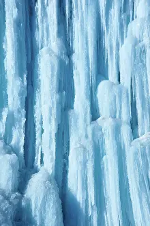 Transparent: Large icicles hang from river bank cliff. Blue color