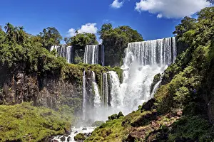Waterfalls: Large waterfalls surrounded by dense vegetation against a blue sky