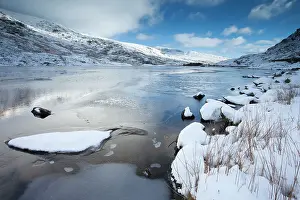Llyn: Llyn Ogwen frozen with snow covered hills in winter