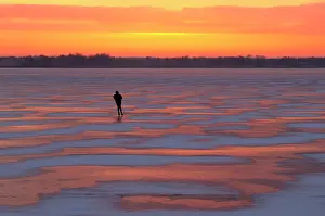 Peat: Lone skater on a frozen lake at sunset