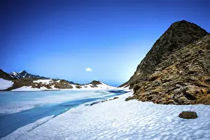 Lonesome: A lonely, frozen lake surrounded by snow-covered mountains