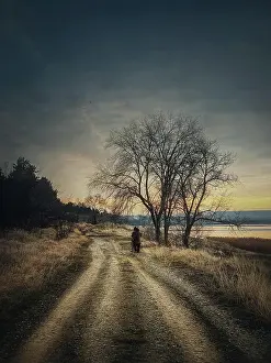 Silence: Lonely nomad person walking a country road. Moody