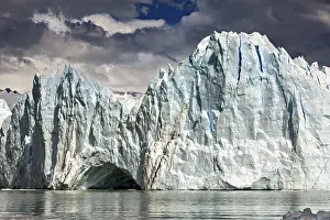 Glaciers: Majestic glacier front under a cloudy sky with mountains in the background