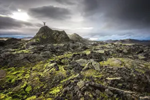 Northeastern: Man on a hill in a black lava field with green moss