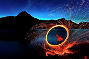 Hour: Man with hoop of fire with sparks on the shore of