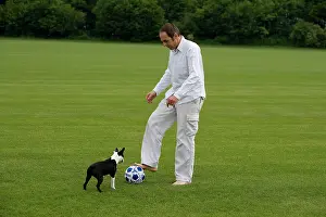 Football: Man - playing football with Boston Terrier dog