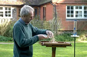 Crumbs: Man putting out crumbs for the birds on bird table