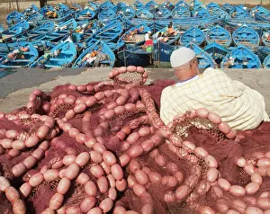 Attractive: Man resting on heap of fishing nets and observing