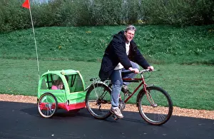 Cycling: Man riding bicycle towing trailer with child