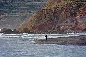 Undulating: Man in front of rock face on undulating sea, churned
