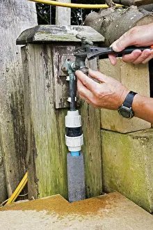 Repairing: Man - with spanner repairing leaking outside garden tap