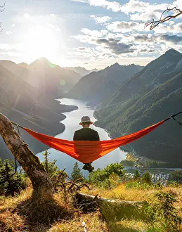Comfortable: Man with a sun hat sitting in an orange hammock