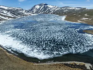 Chain: Melting ice on mountain lake Bessvatn, Mt. Besshn