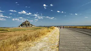 Away: The monastery of Mont Saint-Michel in the distance under a clear sky and slightly cloudy
