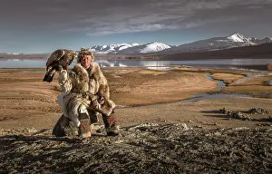 Obedient: Mongolian eagle hunter posted with lake in front