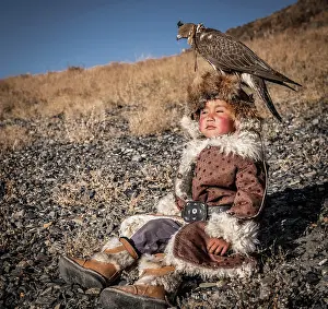 Obedient: Mongolian falcon hunter, little boy posing with