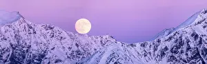 Moonlight: full moon rising into a pink sky in a winter mountain