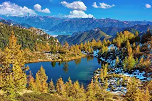 Surrounded: Mountain lake surrounded by autumnal larches, Alpe