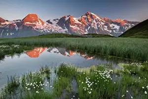 Peop: Mountain peaks are reflected in a small pond, sunrise