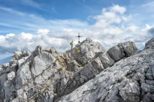 Upper: Mountaineer on the rocky summit of the Watzmann